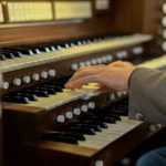 Musician's hands skillfully playing a classical church organ keys in close-up view.