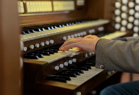 Musician's hands skillfully playing a classical church organ keys in close-up view.