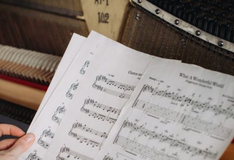 Close-up of a woman's hands turning sheet music at a piano.