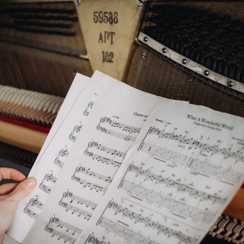 Close-up of a woman's hands turning sheet music at a piano.